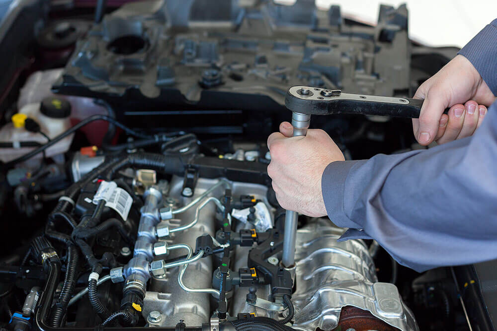 Mechanic using wrench on car engine