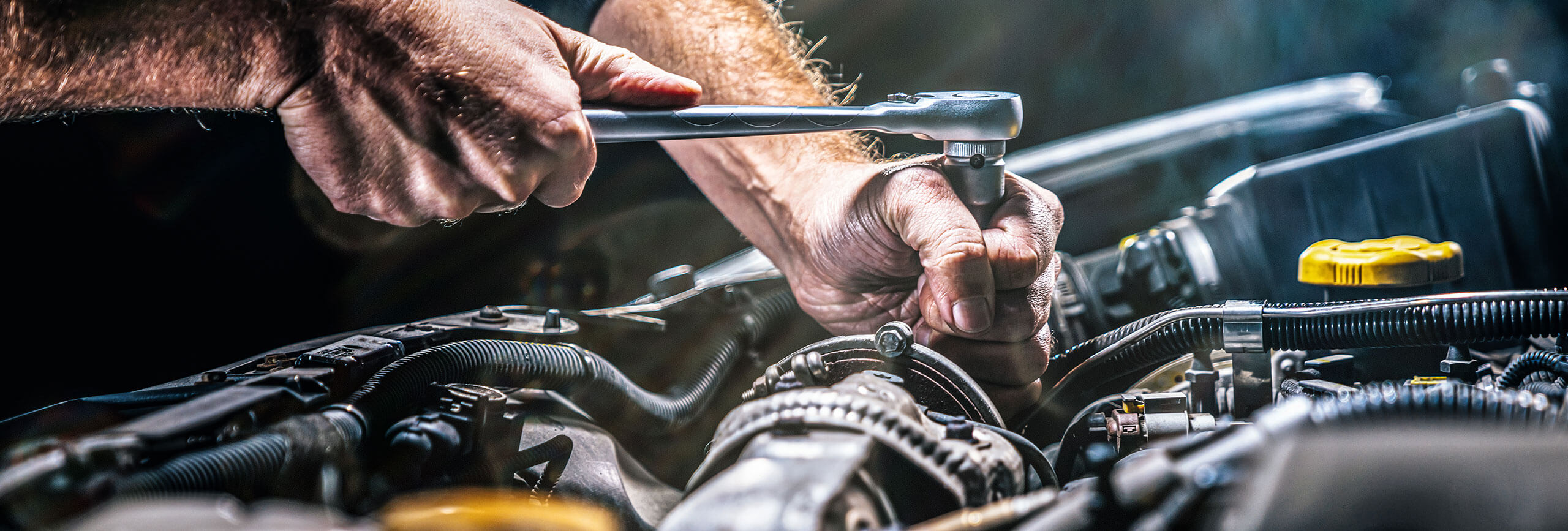 Mechanic tightening car engine bolt with wrench.