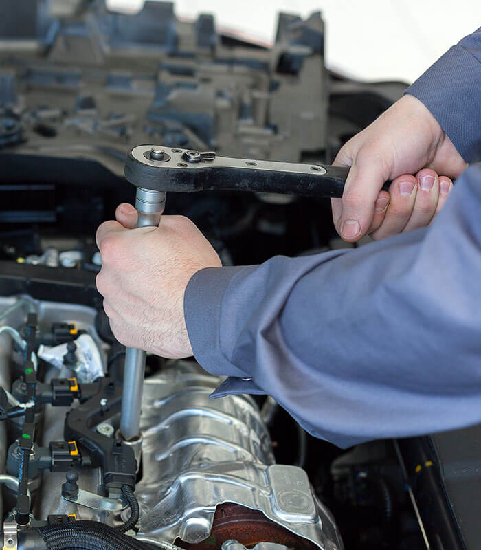 Mechanic using wrench on car engine